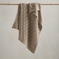 Knitted baby blanket in taupe with cable knit pattern and folded edge