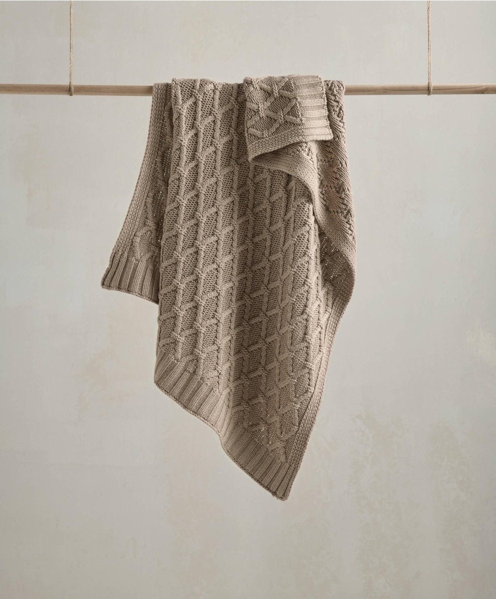 Knitted baby blanket in taupe with cable knit pattern and folded edge