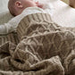 Knitted baby blanket in taupe, cable and textured knit wrap around infant