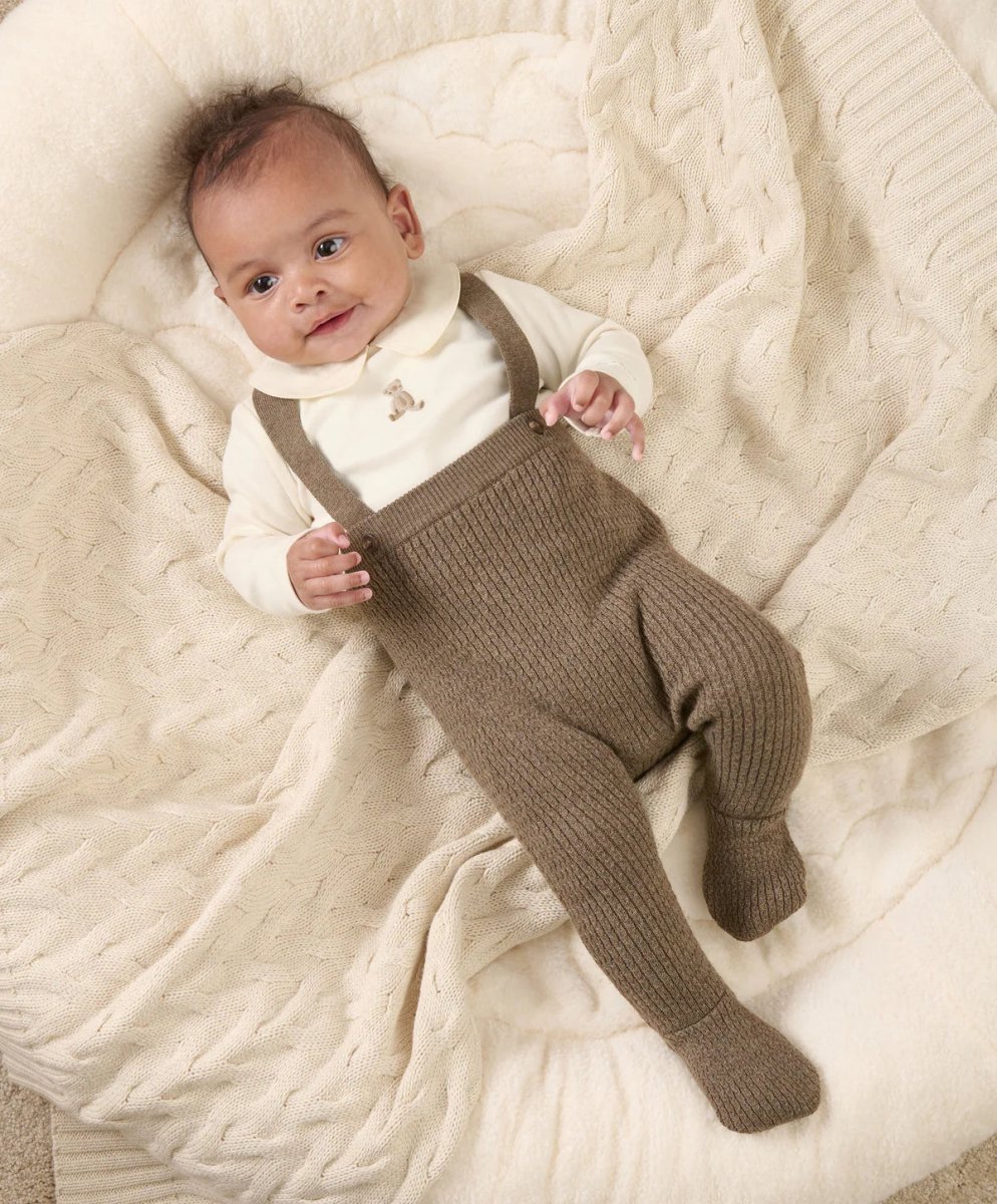 Cream teddy bodysuit with brown knitted dungarees, baby lying down