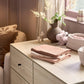 Pack of three muslin cloths, folded pink and cream fabrics stacked on a flat surface