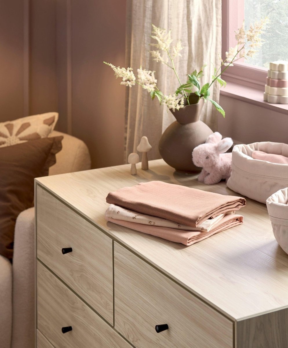 Pack of three muslin cloths, folded pink and cream fabrics stacked on a flat surface