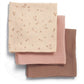 Three muslin cloths folded: cream floral, blush pink solid, and dusty pink solid squares