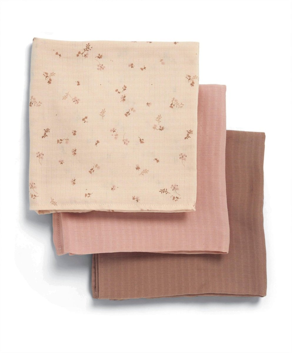 Three muslin cloths folded: cream floral, blush pink solid, and dusty pink solid squares