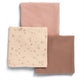 Three muslin cloths folded: cream floral square with two solid pink-toned squares