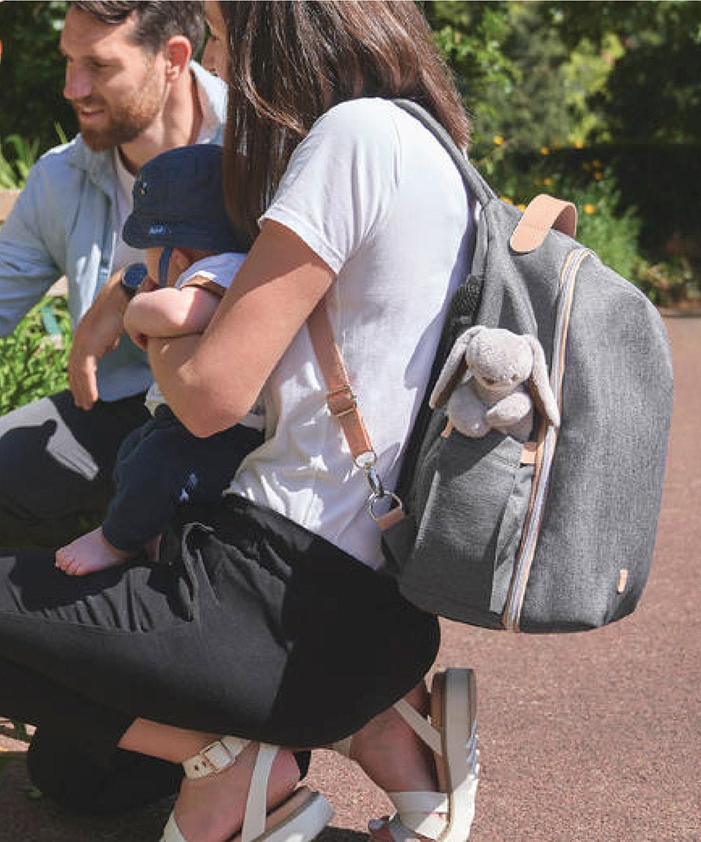 Grey changing bag worn with shoulder straps, front zipper, and exterior pockets