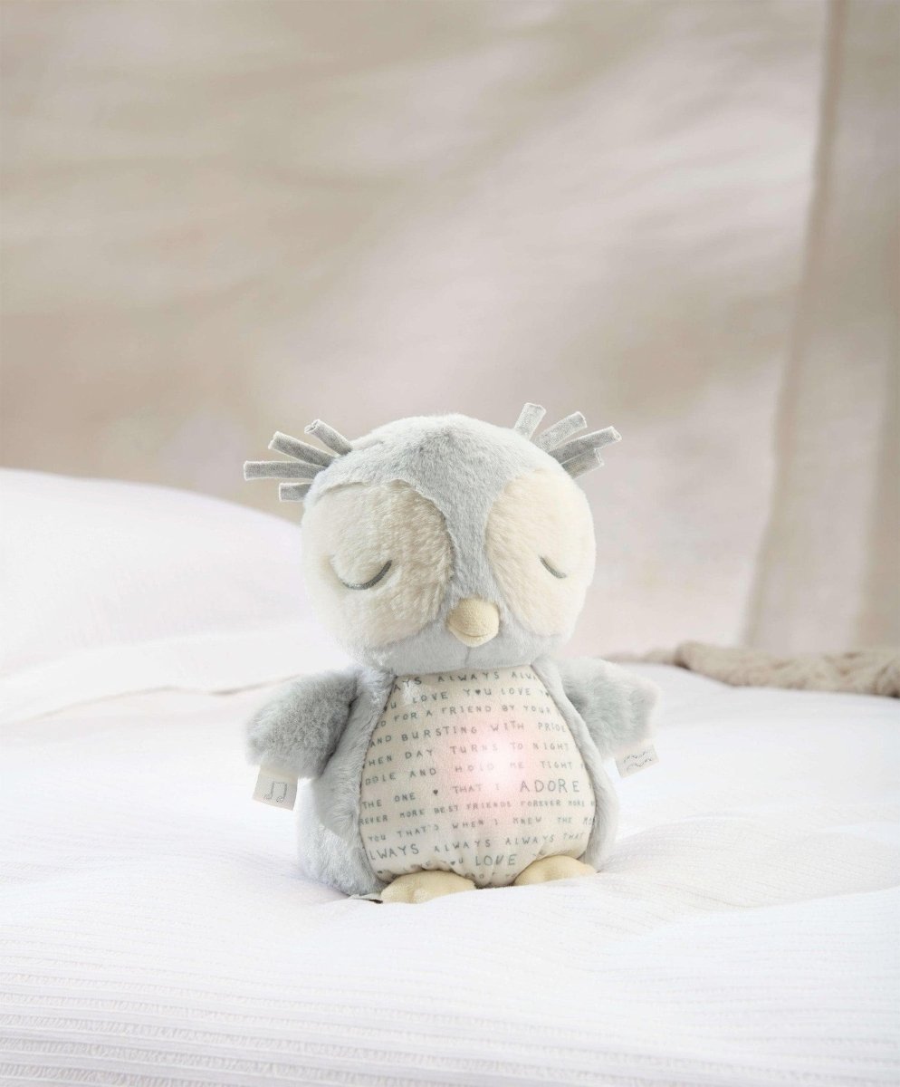 Light gray plush owl sensory toy lying down with eyes closed and beak