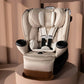 Champagne all-in-one car seat with padded harness and cup holders on dark base, angled.