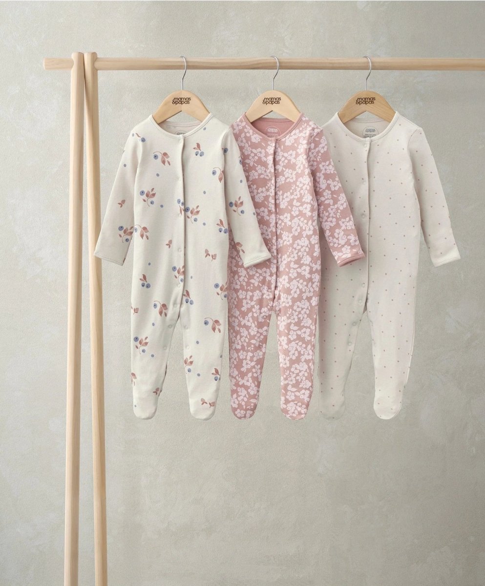 Three long sleeve sleepsuits in prints: white fruit, pink floral, cream starry.