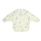 Long-sleeved bib top with light cream dinosaur print, snap neckline and bib front