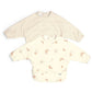 Pair of long-sleeve baby bibs: cream stripe bib and cream animal print bib.