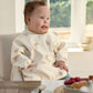 Long-sleeve baby bib in cream with small animal prints, worn by a child.