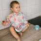 Long-sleeve bib with colorful jungle animal and leaf print, worn by a child