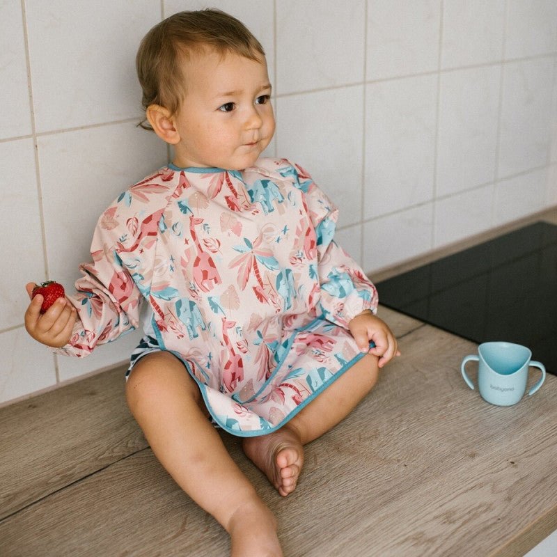 Long-sleeve bib with colorful jungle animal and leaf print, worn by a child