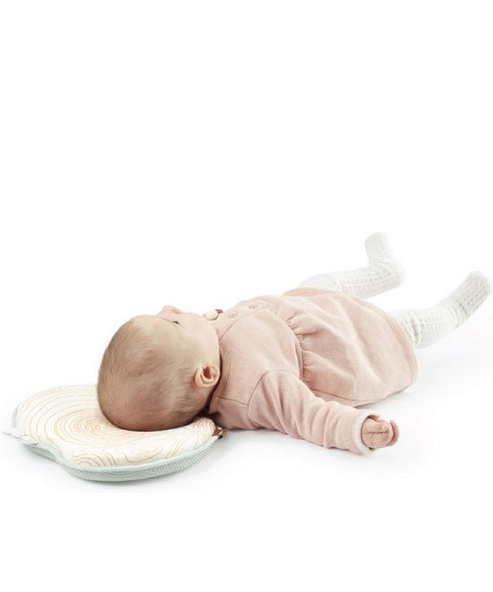 Natural Care headrest with baby lying on it, light pink outfit and swirl cover