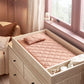 Quilted blush changing pad with wildflower print in a light wood drawer frame