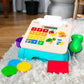 Blue toy cash register with number grid, fruit-themed keys, and colorful plastic cards
