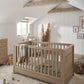 Oak cot bed with vertical slats and fitted bedding