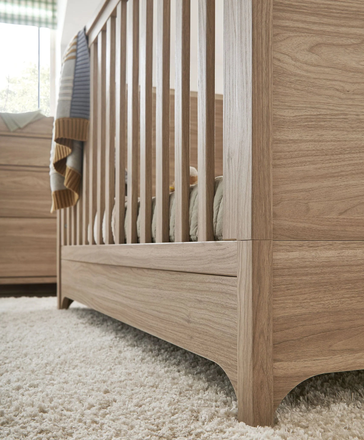 Oak cot bed corner with vertical slats and rounded lower base panel
