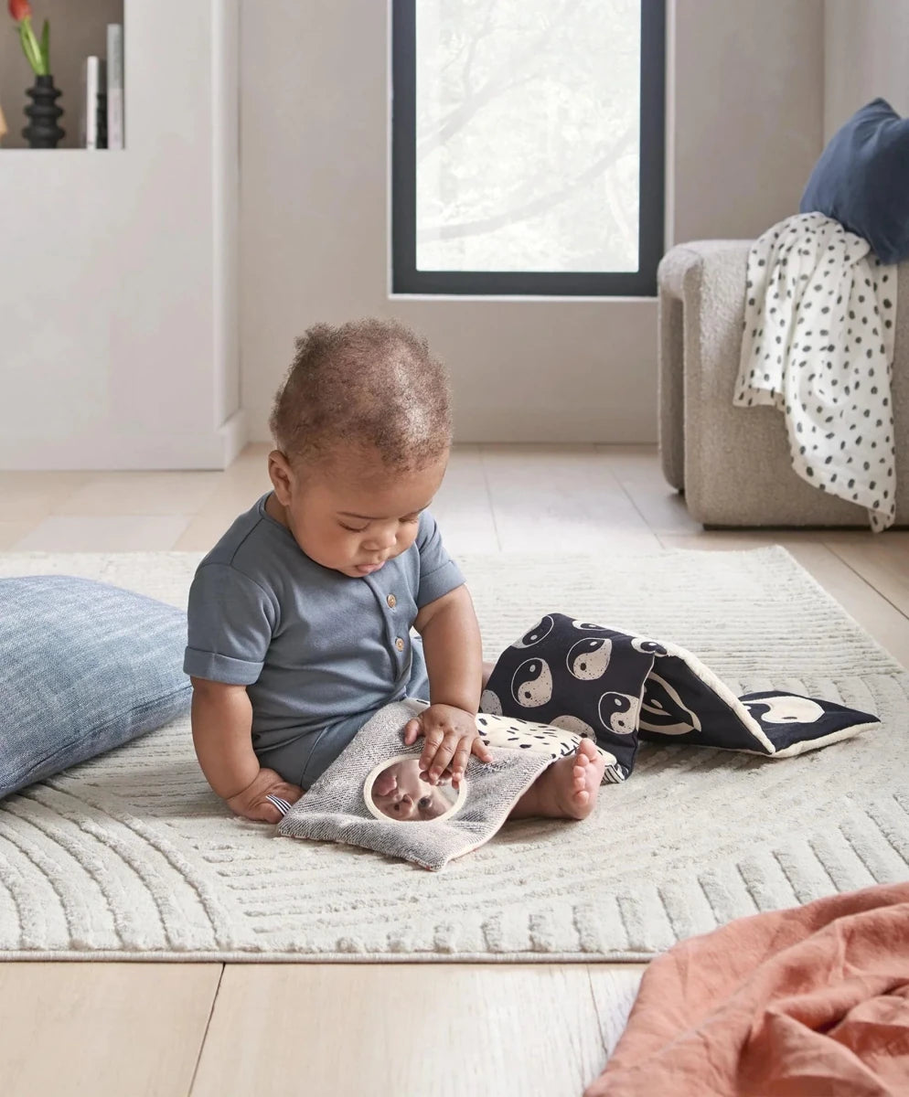 Baby playing with folding fabric book featuring fox and yin-yang patterns