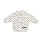 Long-sleeve baby bib, off-white with scattered black cheetah spot print