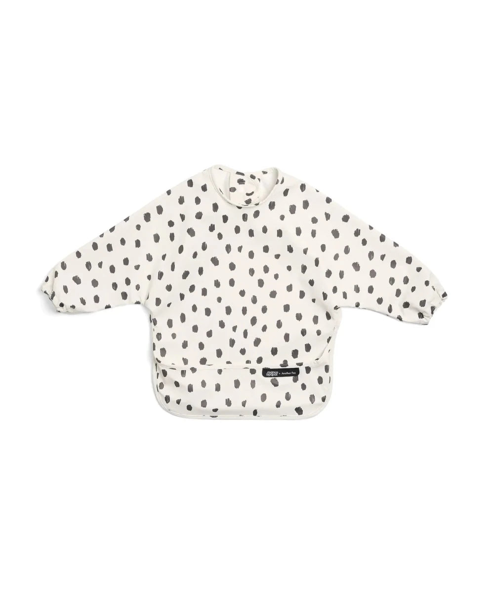 Long-sleeve baby bib, off-white with scattered black cheetah spot print