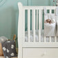 White Mia cotbed side with hanging storage and grey elephant cushion