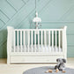 White Mia cotbed with slatted frame and plush toys on a round rug