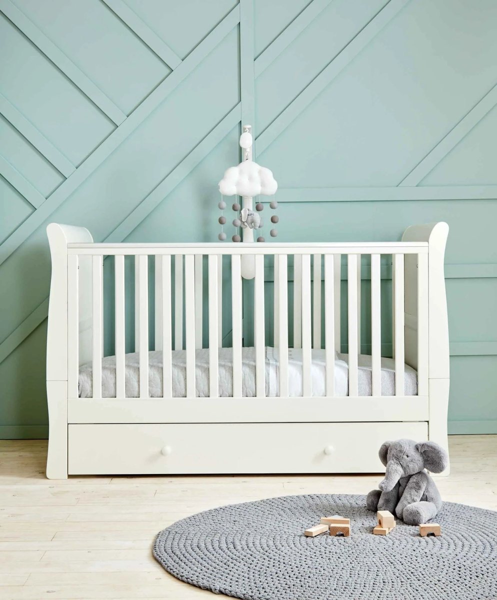 White Mia cotbed with slatted frame and plush toys on a round rug