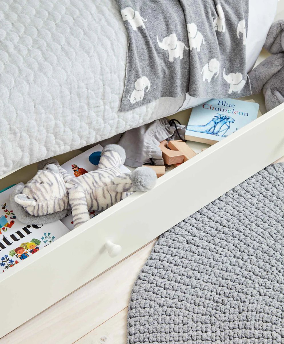 White Mia cotbed with grey elephant-patterned bedding and folded quilt
