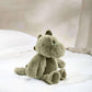 Green plush dinosaur toy with small horn, front paws tucked, stitched eyes