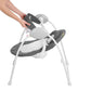 Infant swing side view with gray seat pad, hanging toy, and white frame