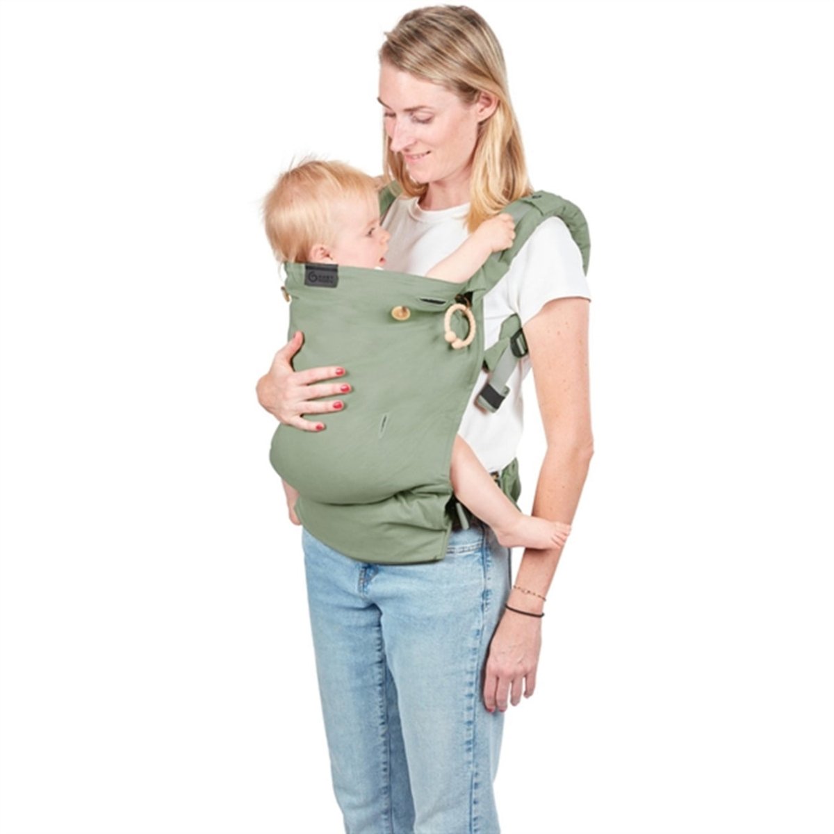 Sage green baby carrier worn by caregiver with newborn supported inside