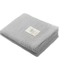 Grey knitted bamboo blanket, folded with beige stitched animal label