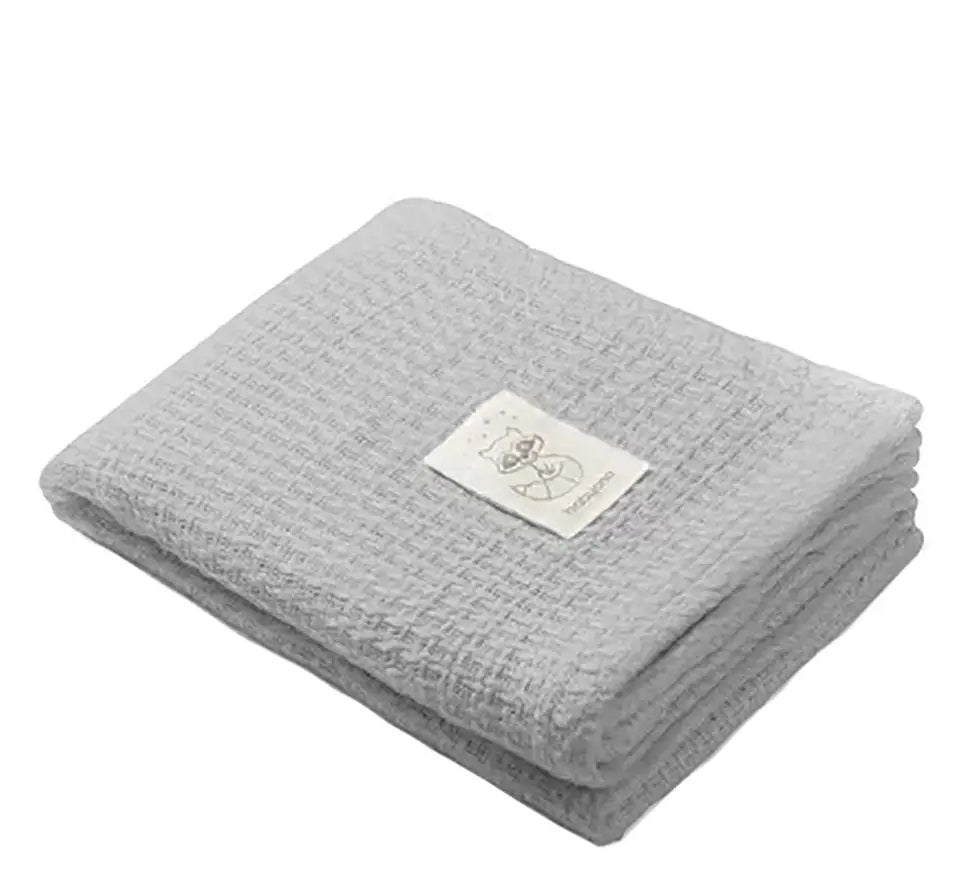 Grey knitted bamboo blanket, folded with beige stitched animal label