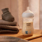 Natural Response baby bottle with handle, shown with milk inside and animal graphic