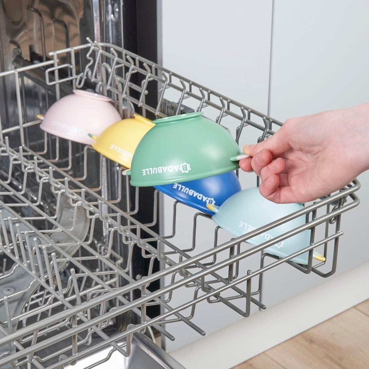 Non-slip bowls with flexible spoons set, multicolor bowls in dishwasher rack, hand holding bowl
