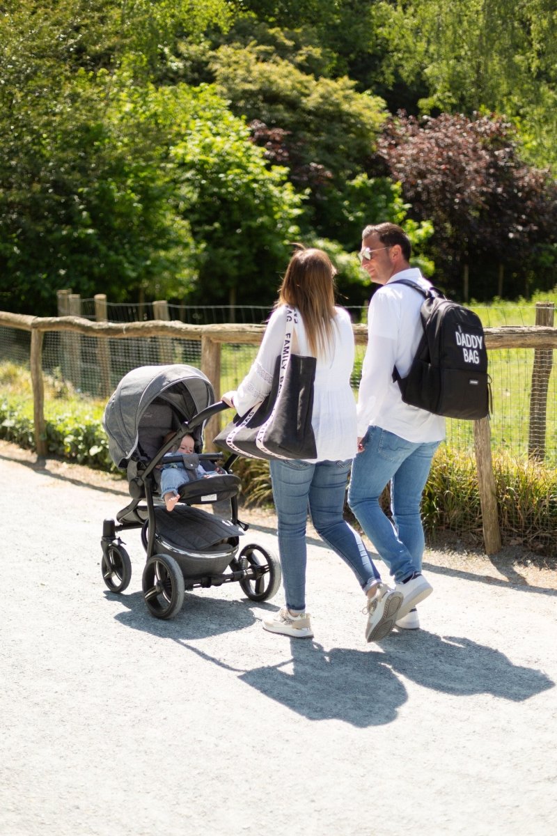 Nursery backpack worn by parent with dark 'DADDY BAG' print, paired with stroller
