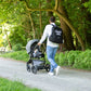 Nursery backpack on adult pushing stroller, dark 'DADDY BAG' print on back