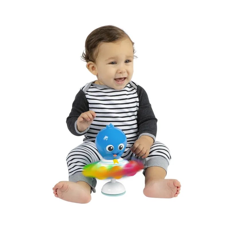 Blue ocean toy figure held by a smiling baby, on round white base.