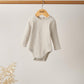 Oatmeal ribbed long-sleeve baby bodysuit hanging on wooden hanger