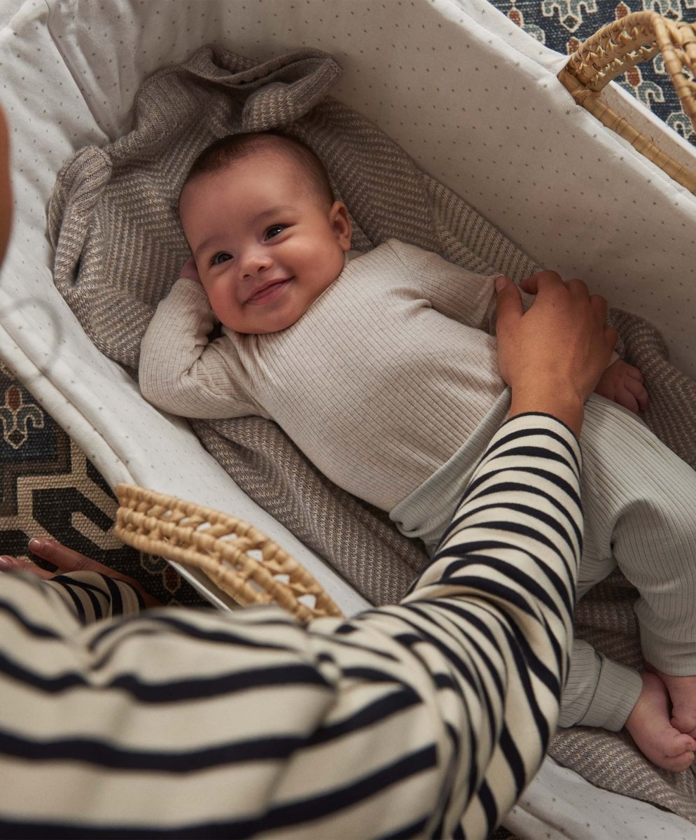 Oatmeal ribbed long-sleeve baby bodysuit on infant in a soft knit blanket