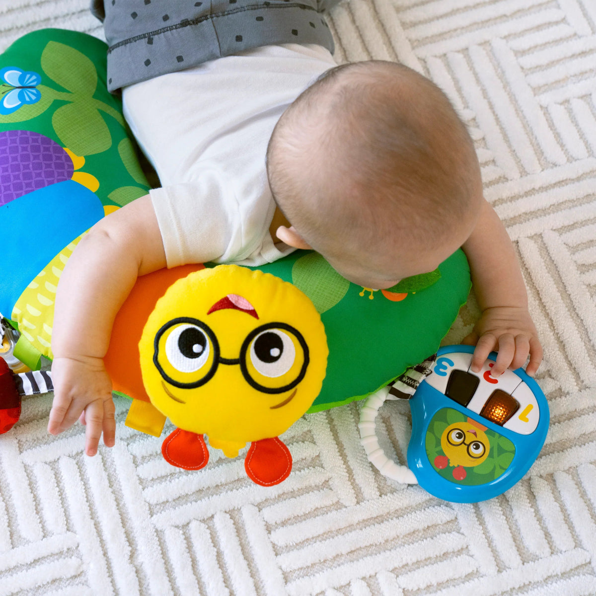 Green activity pillow for tummy time with yellow caterpillar face and blue mirror