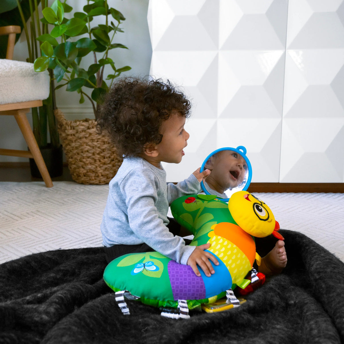 Green caterpillar tummy time activity pillow with plush toys and baby-safe mirror loop