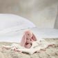 Pink bunny comforter with small plush bunny on folded white blanket with pink accents