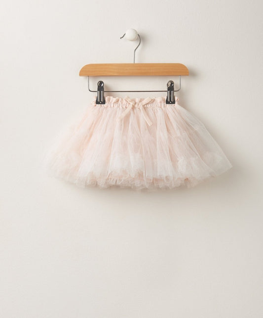 Light pink tulle tutu skirt hanging on wooden hanger with clips
