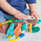 Plush activity toy with teal spine, orange patterned panel, and crinkly dangling straps.