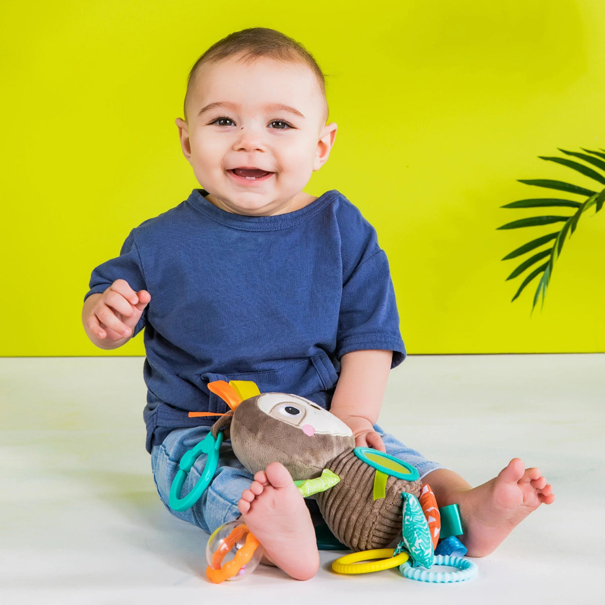 Plush take-along activity toy with dangling sensory parts and colorful striped accents.