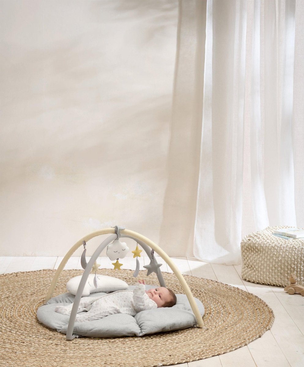 Round beige playmat with gray play arch and hanging cloud, star and moon toys