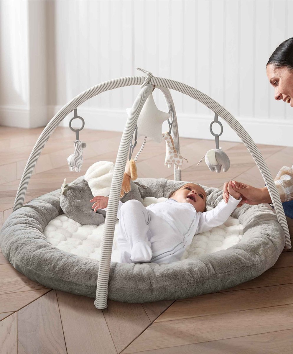 Elephant playmat gym with arch, gray round cushion, and hanging plush toys with parent